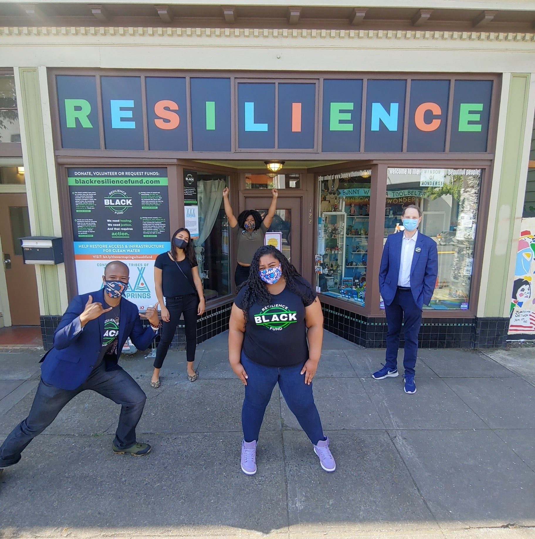 People pose in front on a storefront that says Resilience in block letters.