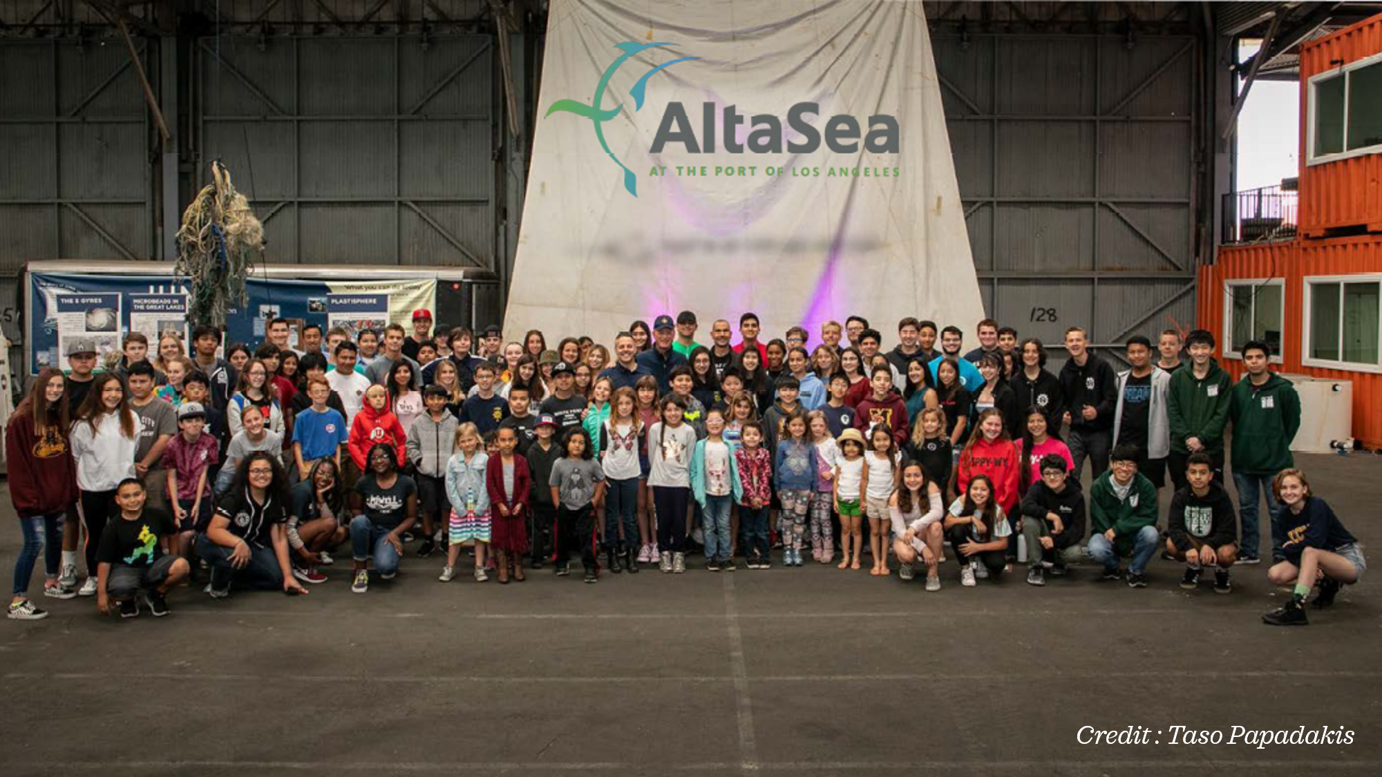 A large group of people photographed from far away in front of an AltaSea banner.