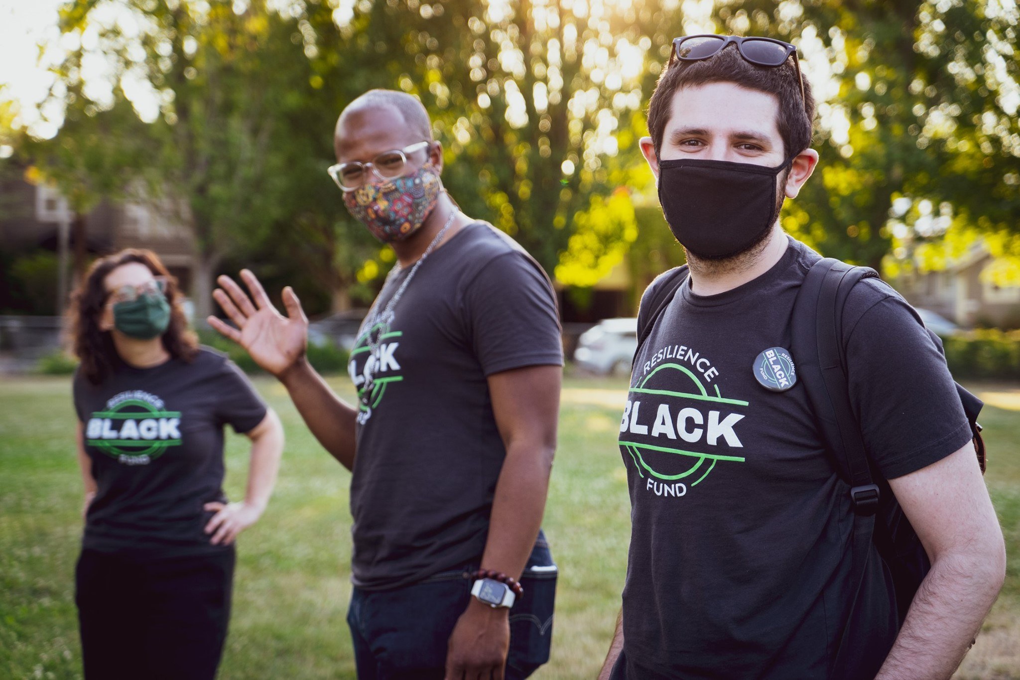 Three people stand in Black Resilience Fund t-shirts, wearing masks.