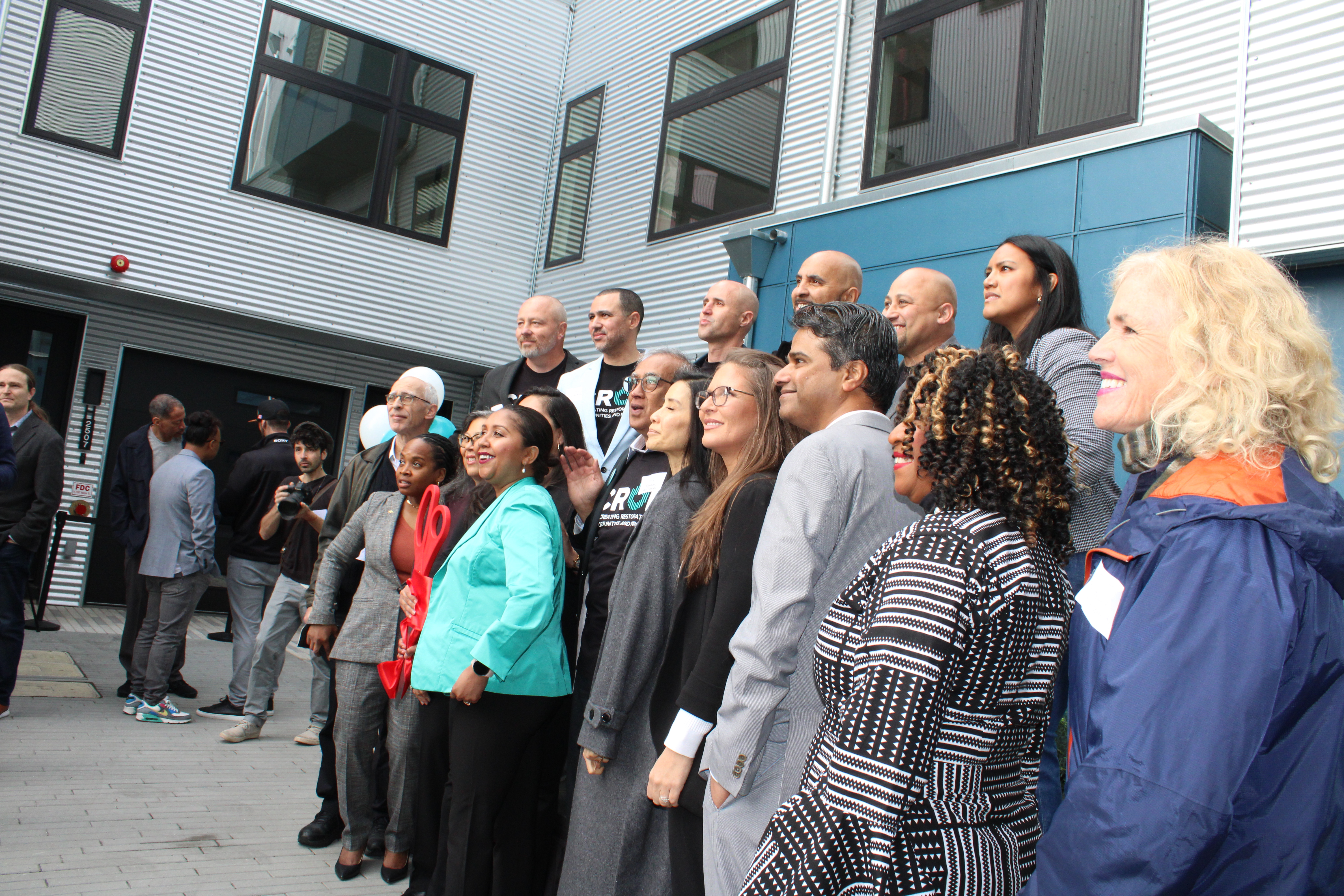 CROP Oakland Grand Opening in March 2023. A line of CROP staff and supporters including Kat Taylor pose for a photo on CROP's campus
