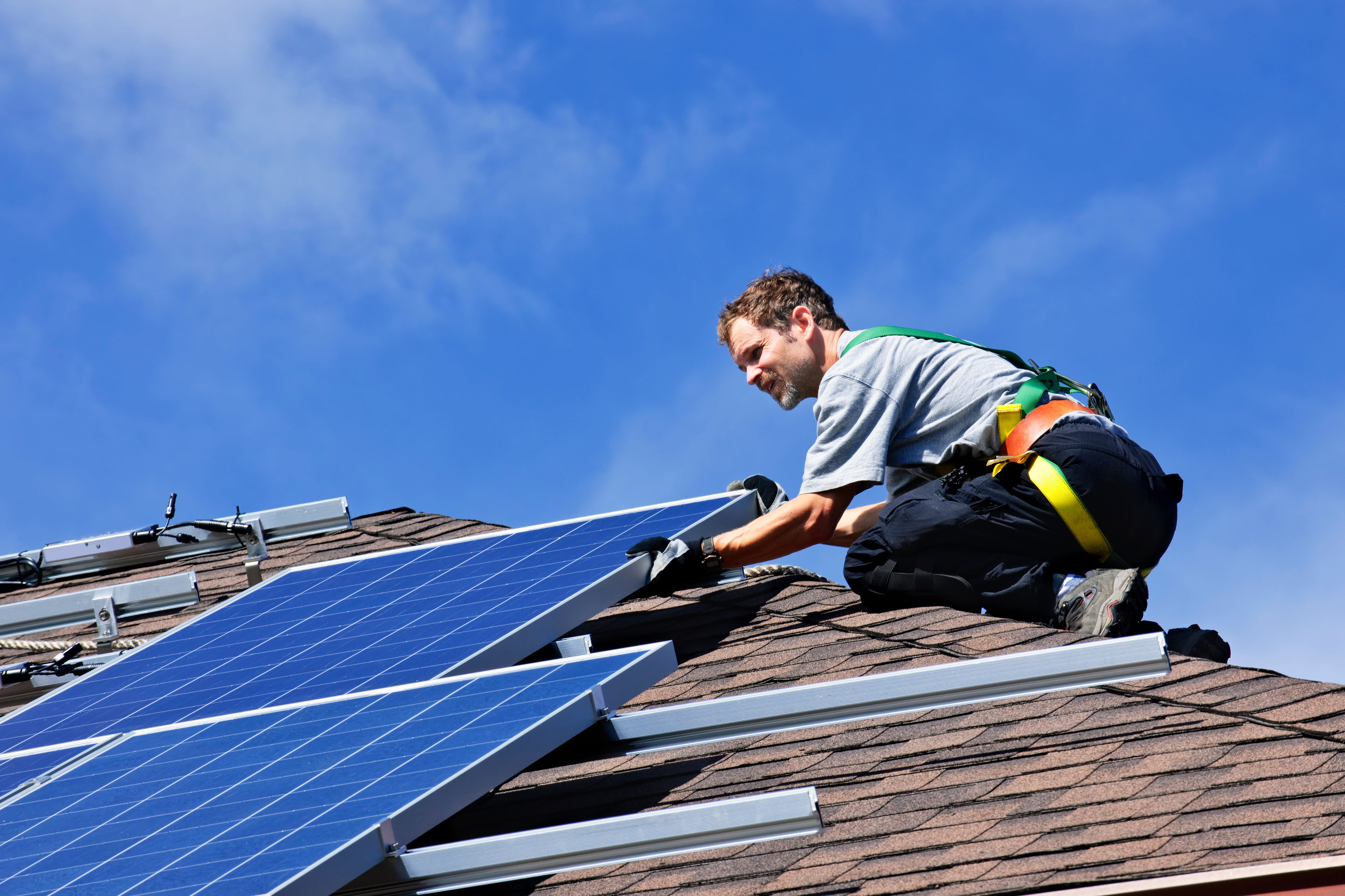 Man installing solar panels on a house roof