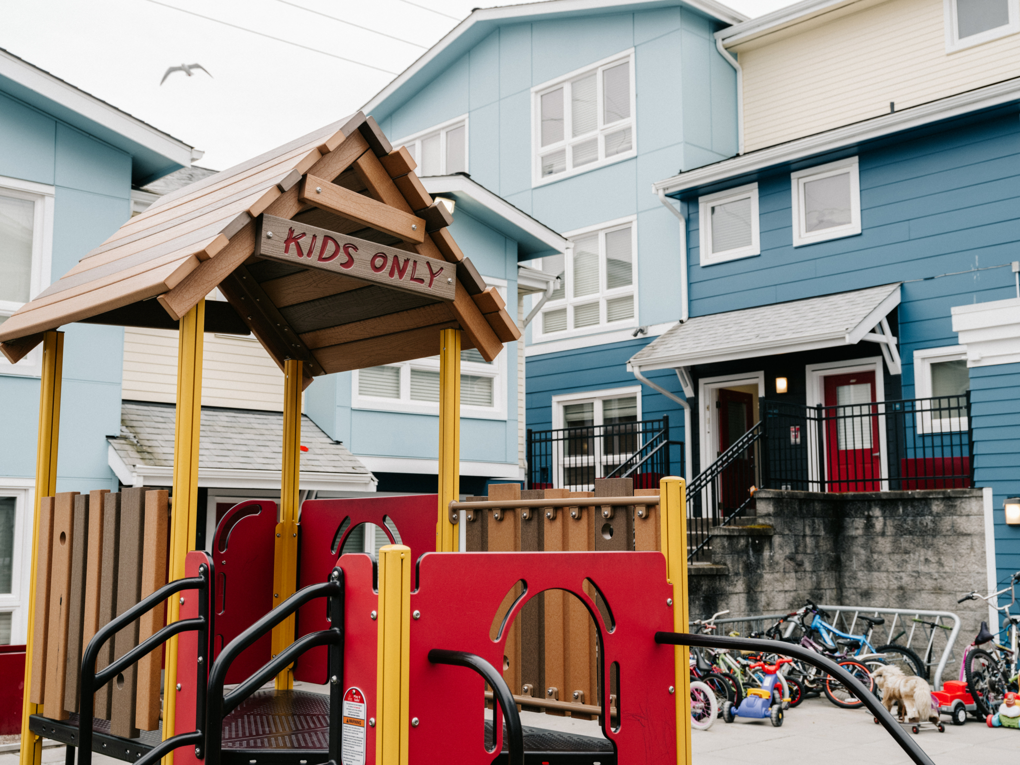 A play structure with a "Kids Only" sign in front of a Housing Hope affordable housing development.