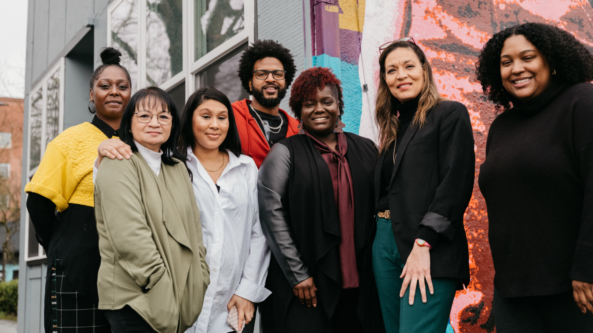 Seven team members from MESO stand in front of a mural.