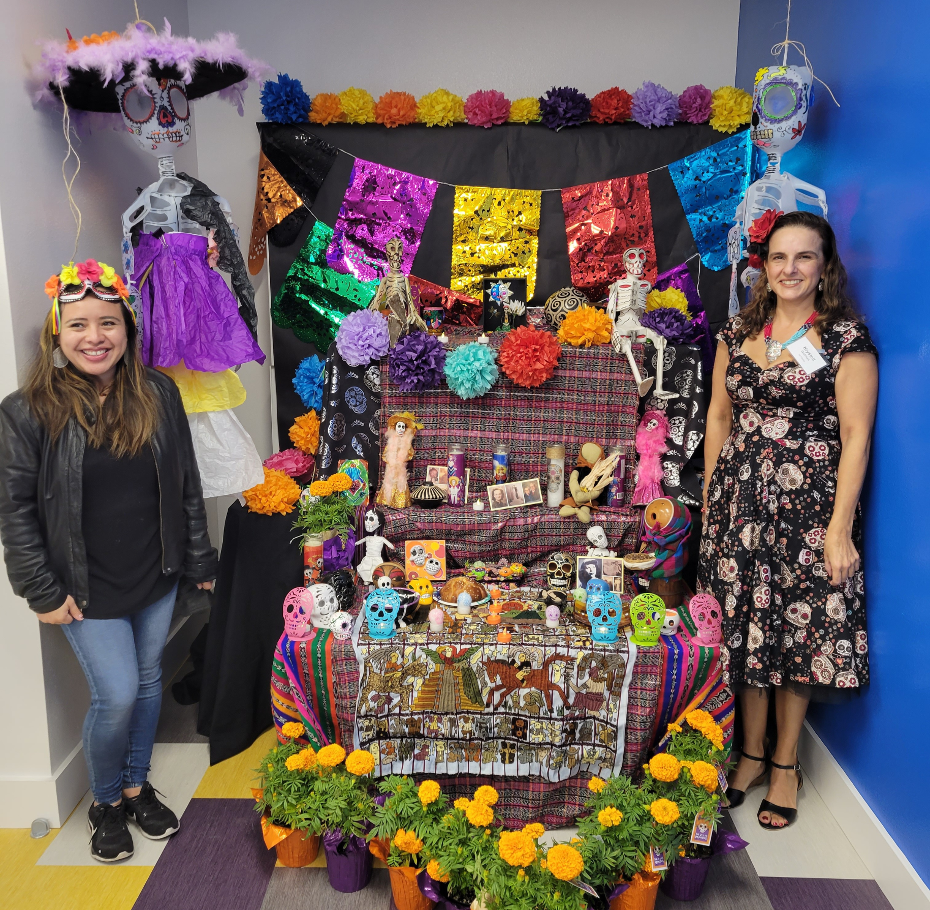 Two Plazita Schools staff members stand with a cultural display