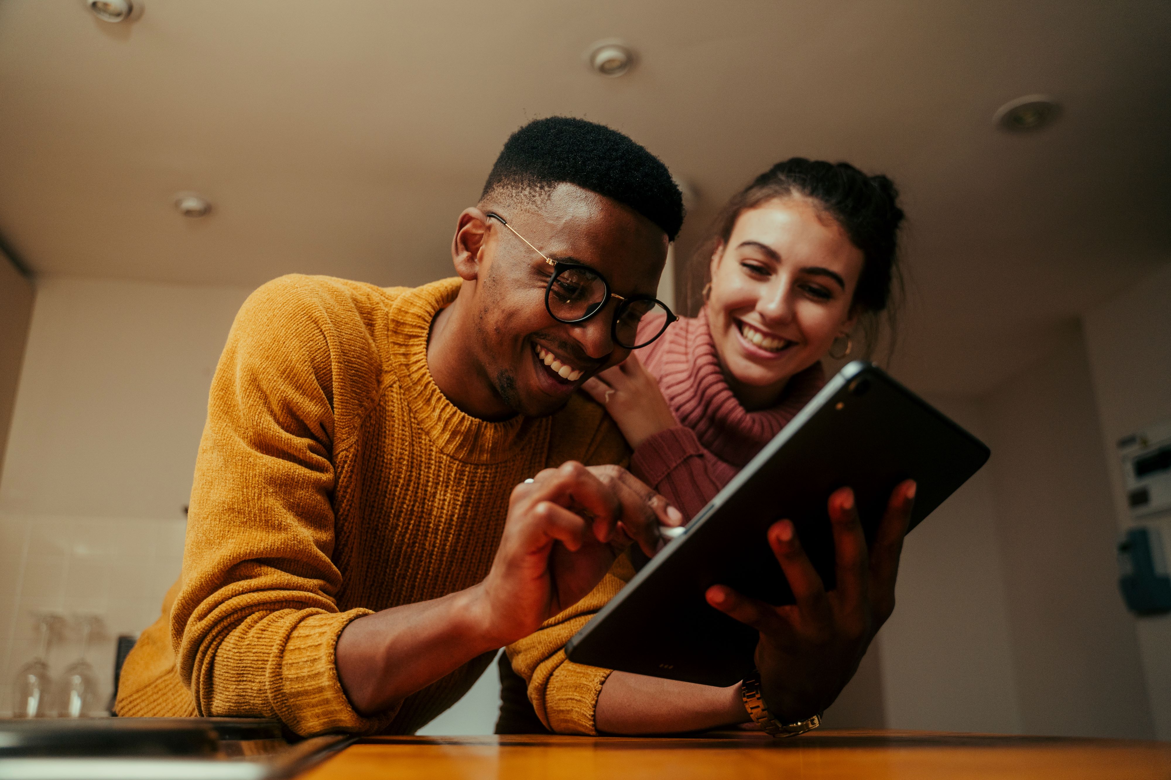 A man and a woman smile while looking at a tablet device
