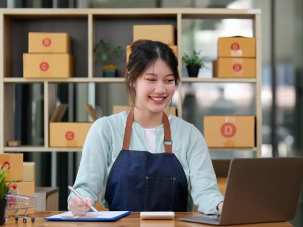 Woman small business owner smiles while looking at her computer