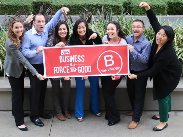 Blue Garnet team holding a B Corp sign