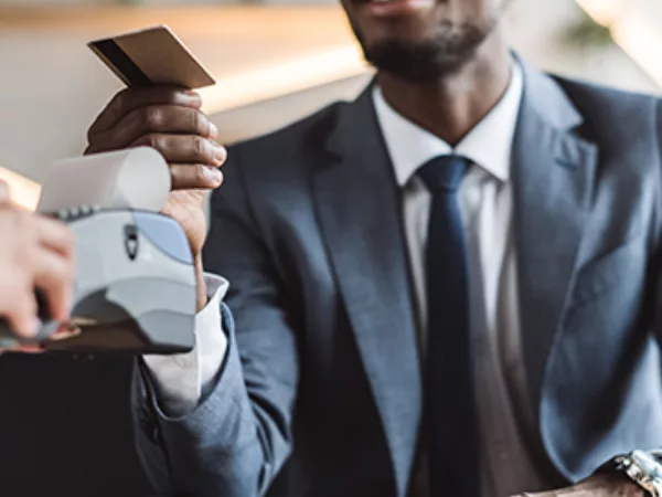 A man wearing a suit pays for a cup of coffee using a credit card