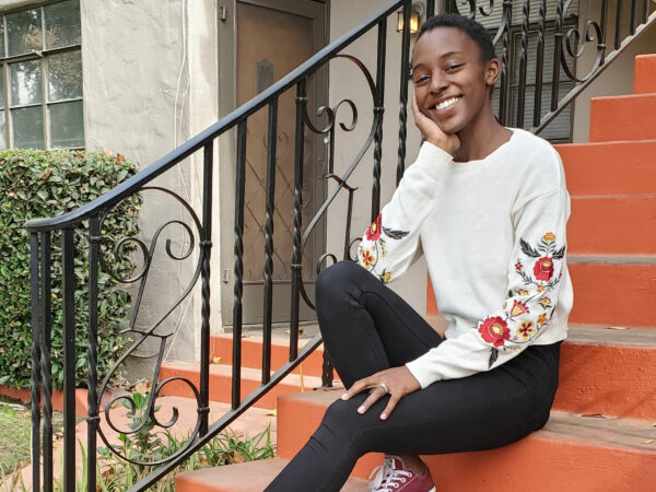 Beneficial State Bank client Alyssa Ndombeson, owner of Good Fill in Fresno, sits on steps, smiling at the camera.