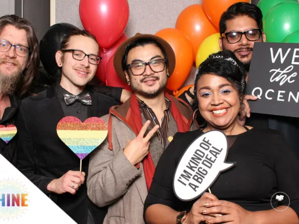 A group of five people post with Pride flag-themed items