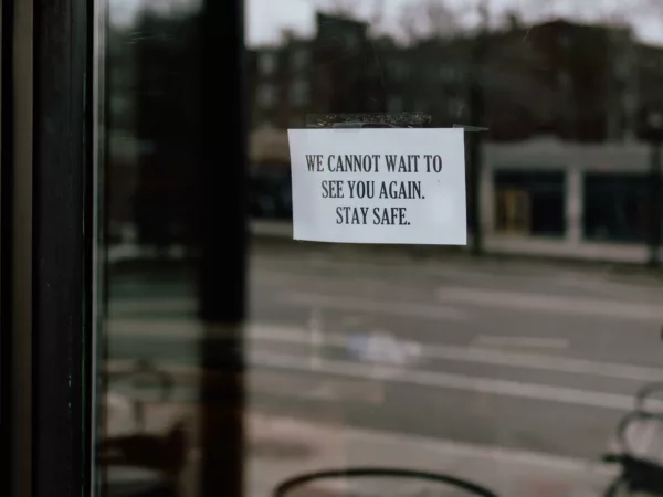 A sign on a business window that says "We cannot wait to see you again. Stay safe."