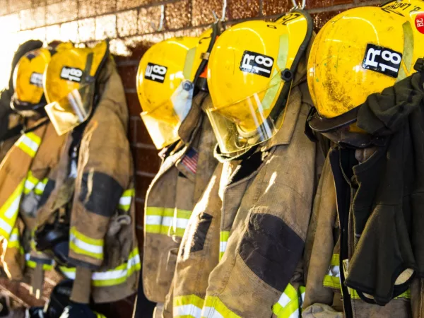 A line of firefighter suits hanging on hooks