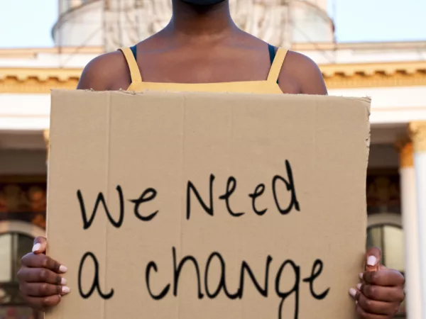 Person holding a sign that says "We need a change"