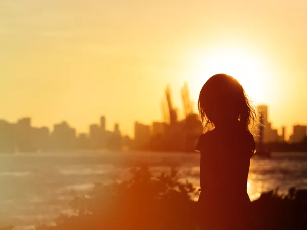 Silhouette of girl looking into sunset over city
