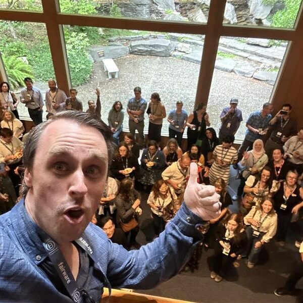 Craig Hill stands in front of a crowd of people and gives a thumbs up at BLD Portland