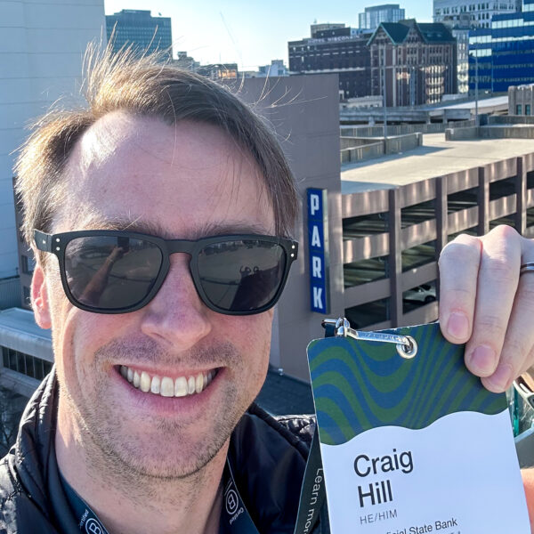 Craig Hill holds up his Champions Retreat name tag on a rooftop patio in Milwaukee
