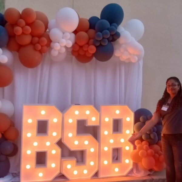 Isabella Smith, Beneficial State Bank's recruiter, stands in front of a celebratory display of light-up BSB letters and balloons at our Porterville location.