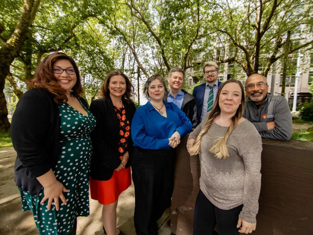 A group of Beneficial State Bank staff in a wooded area in Seattle, smiling at the camera.