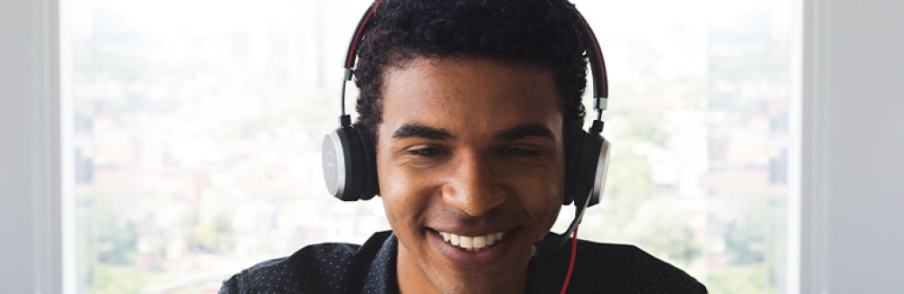 A man wears headphones and smiles
