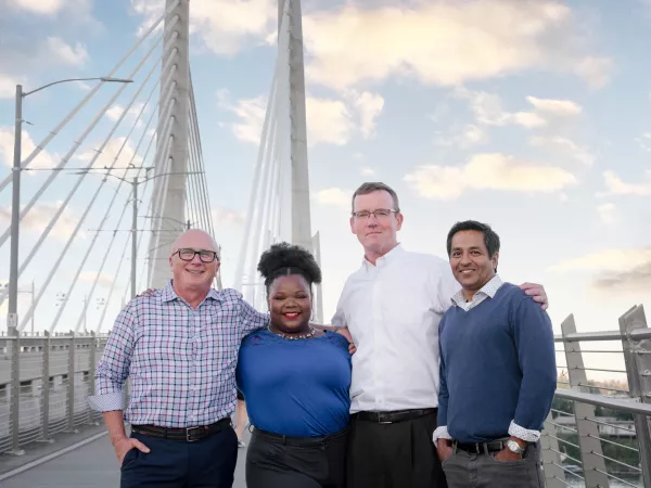Four Bridge City Law Firm partners standing on a bridge