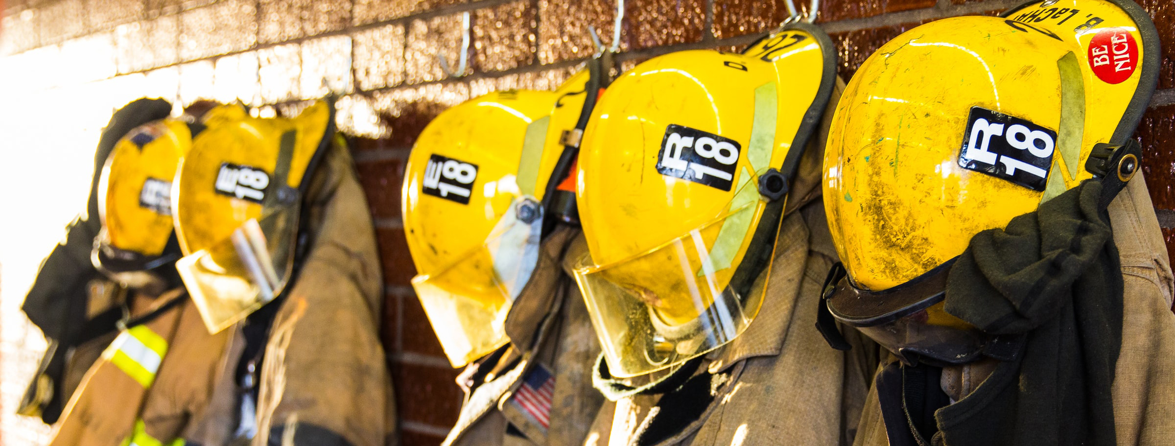 A line of firefighter suits hanging on hooks A line of firefighter suits hanging on hooks